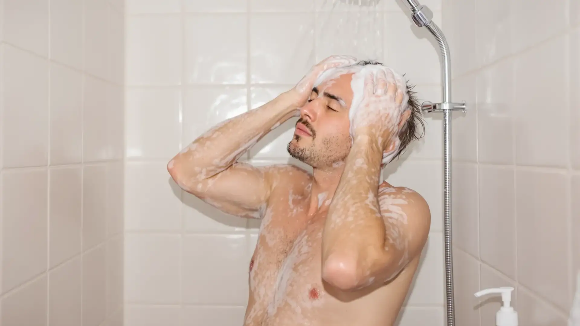 Man washing thinning hair with shampoo in the shower.