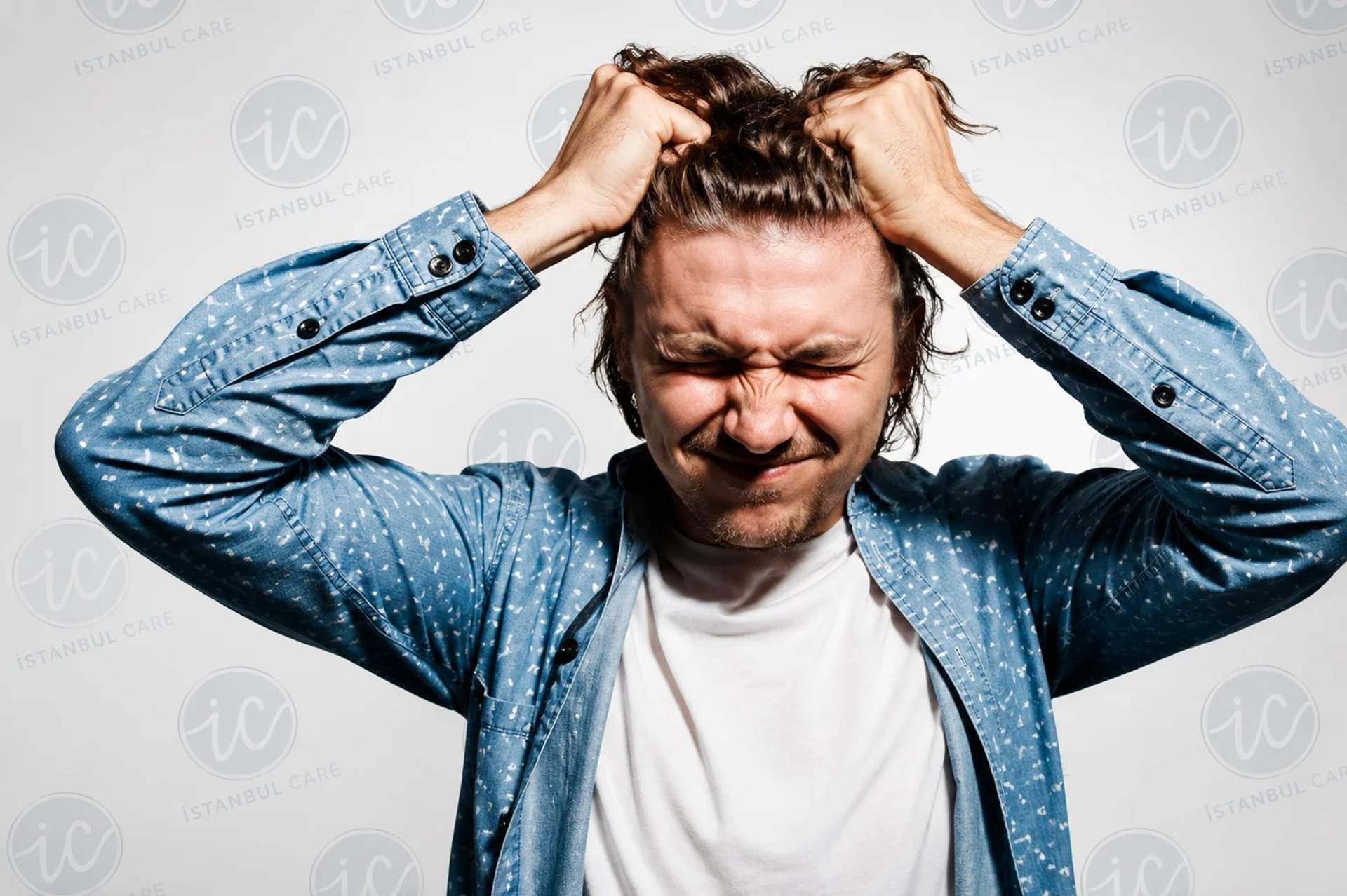 Uomo frustrato che si tira i capelli con entrambe le mani, illustra la perdita di capelli da stress.